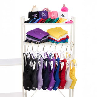 Colorful leotards and bags on a white rack against a white background