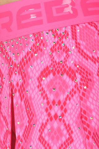 Close-up of a bright pink snakeskin-patterned garment with rhinestone embellishments and a matching pink waistband featuring embossed lettering.