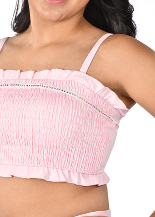 Pink crop top with ruffled details and thin straps on a white background