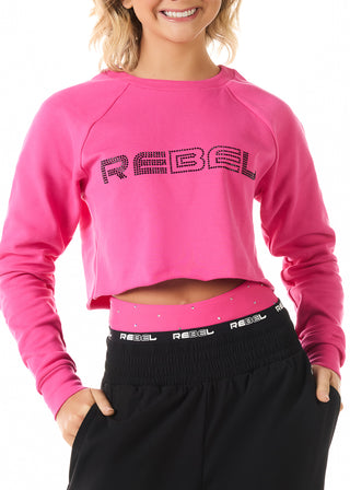Person wearing a pink 'REBEL' sweatshirt with black pants on a white background